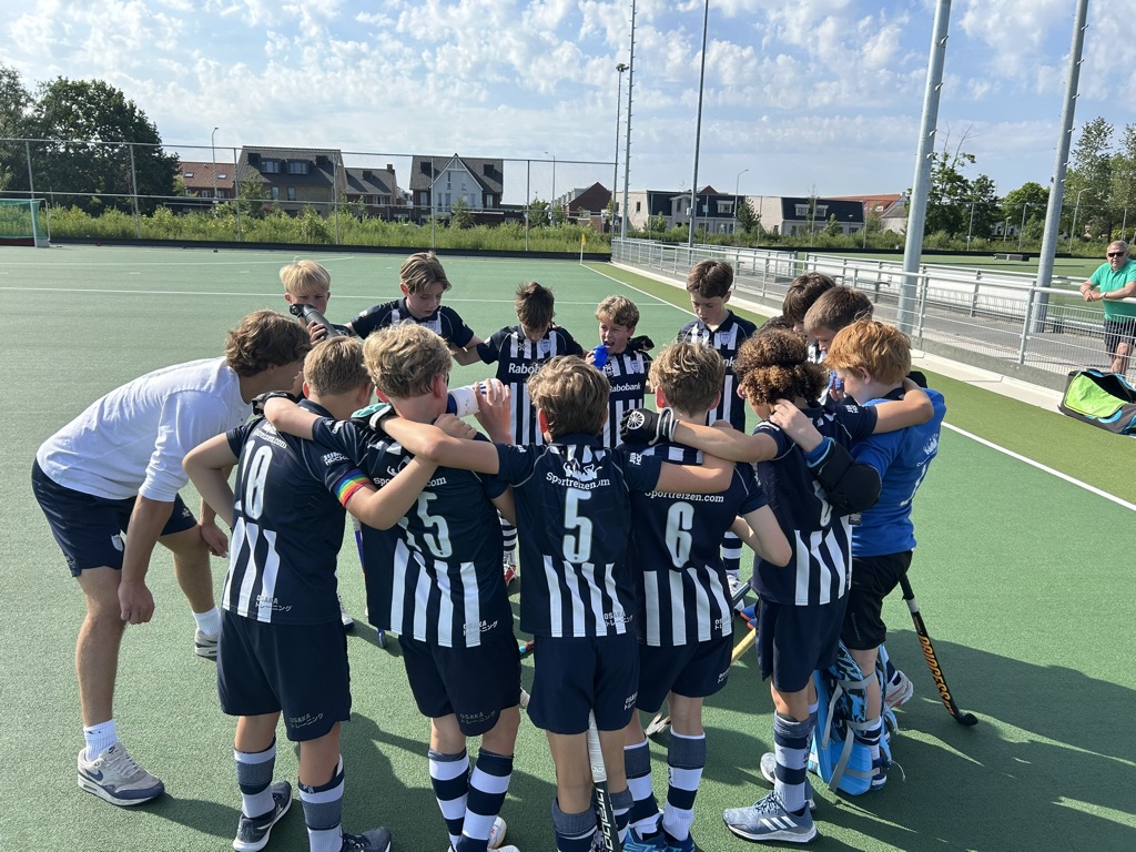 Jeugdhockeyteam in een huddle met de coach voor de wedstrijd