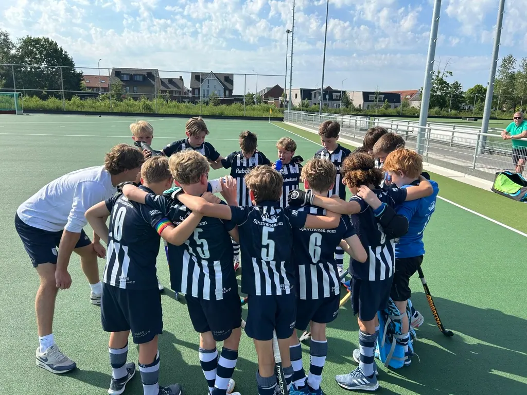 Jeugdhockeyteam in een huddle met de coach voor de wedstrijd